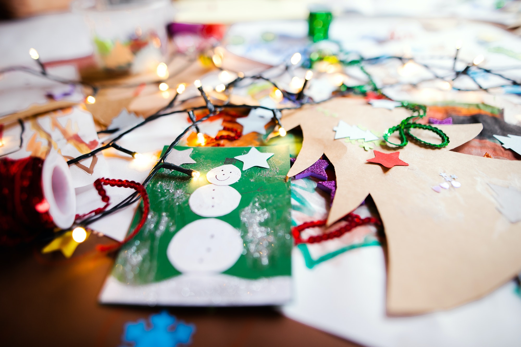 Children's paintings and Christmas paper art and craft on table