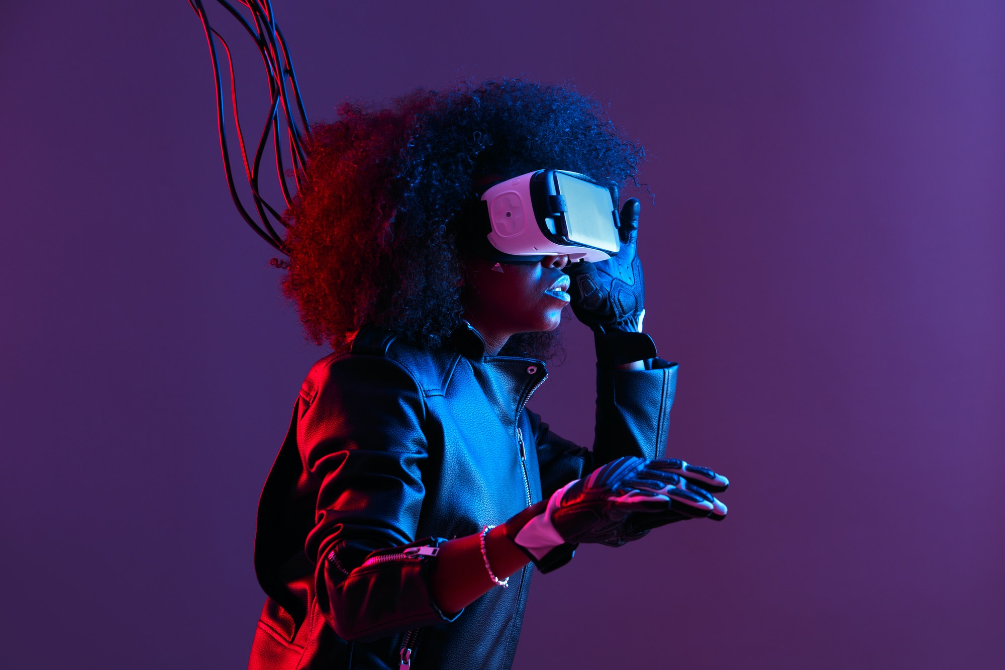 Mod curly dark haired girl dressed in black leather jacket and gloves uses the virtual reality